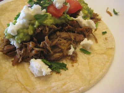 Slow Cooker Mexican Pulled Pork on a taco with queso fresco Slow Cooker Mexican Pork