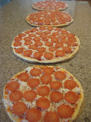 Four pre-made pizzas topped with sauce, cheese and pepperoni