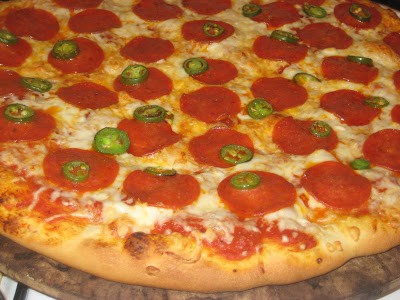 Close up of a pizza topped with pepperoni and Jalapeno slices.