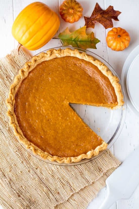 Bird's eye view of pumpkin pie with a slice missing out of it. 