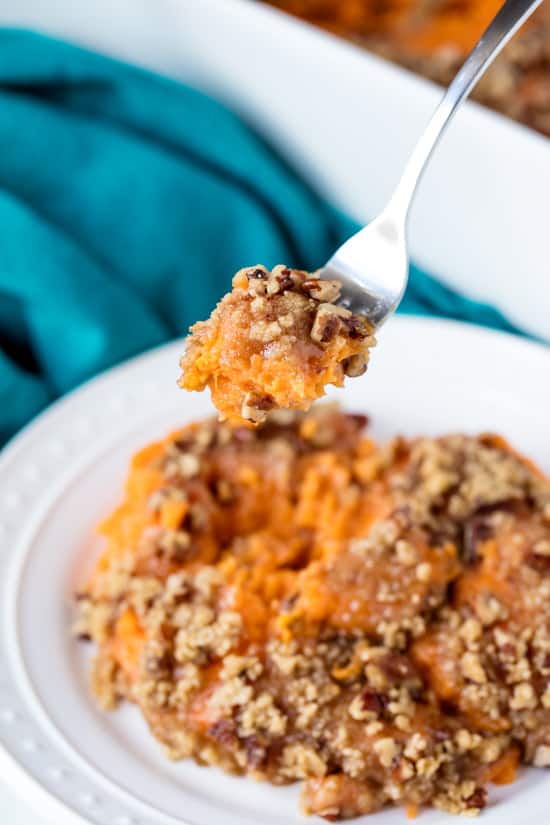 A fork takes a bite of Best Sweet Potato Casserole from a plate