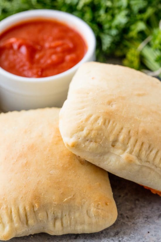 Tasche calde fatte in casa con una ciotola di salsa marinara da intingere