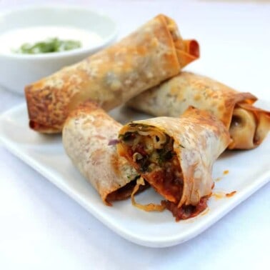 Mexican-Eggroll on a white plate with one cut in half to show the insides.
