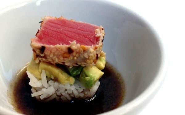 Ahi Avocado sushi in a bowl of soy sauce.