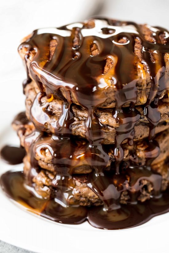 Chocolate and caramel syrup drizzled over a stack of decadent chocolate pancakes