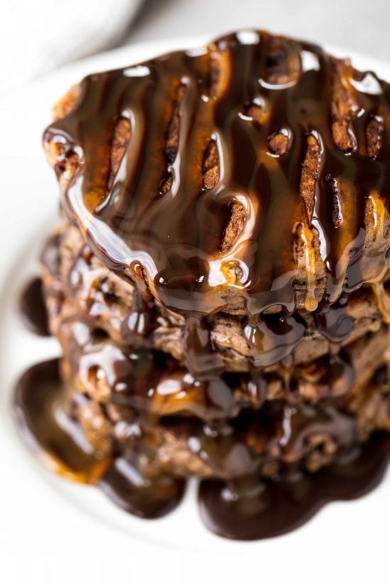 Chocolate and caramel syrup drizzled over a stack of decadent chocolate pancakes