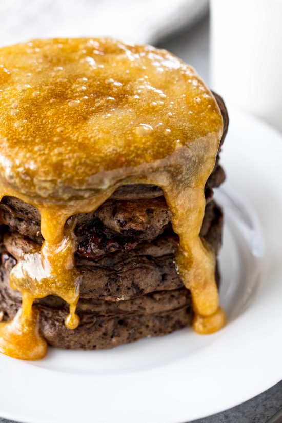 Homemade caramel syrup drizzled over a stack of decadent chocolate pancakes