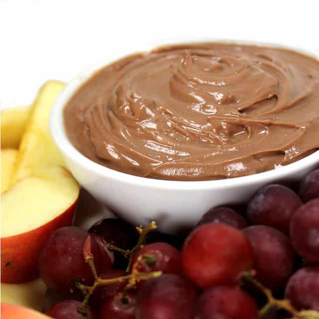 Nutella Fruit Dip in a white bowl surronded by apples and grapes.