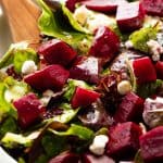 Beet Salad in a white bowl with a wooden spoon in it.