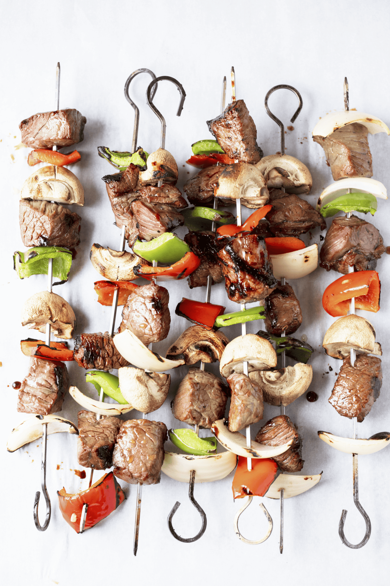 Seven Marinated Steak Kebabs on a countertop.