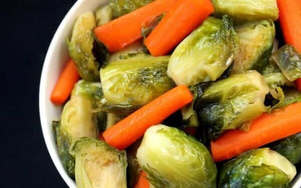 Maple Brussel Sprouts and carrots in a white bowl.
