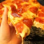 Hand holding a slice of pizza