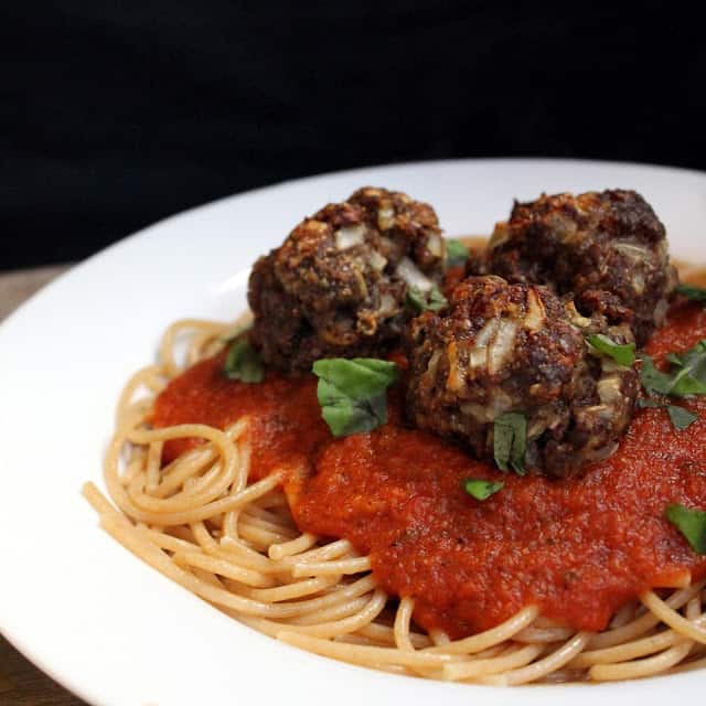 Healthy Baked Meatballs top a plate of spaghetti with marinara sauce