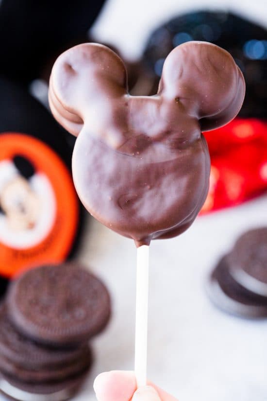 Rachel holds up a Mickey Mouse Oreo Pop with Mickey and Minnie Mouse hats and Oreos in the background