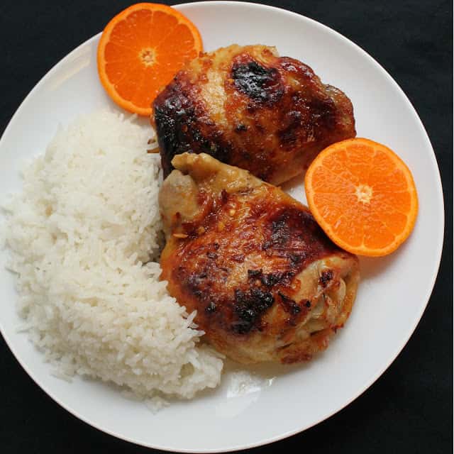 Bird's eye view of Orange Glazed Chicken Thighs served with coconut rice and fresh sliced oranges