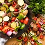 Fresh vegetables tossed with seasoning in a pan and grilled veggie kebabs on metal skewers on a cutting board