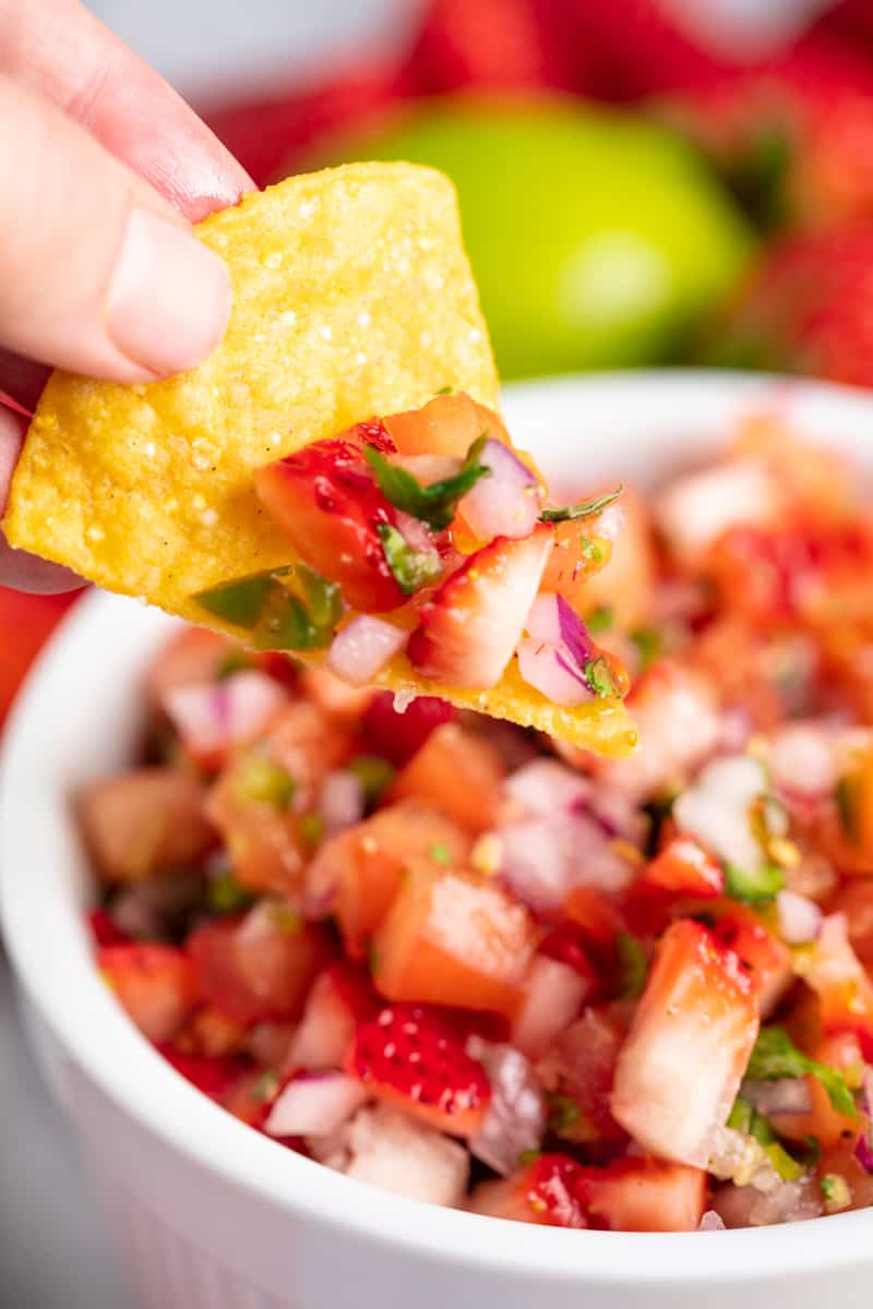 A chip dips into a bowl of Strawberry Salsa