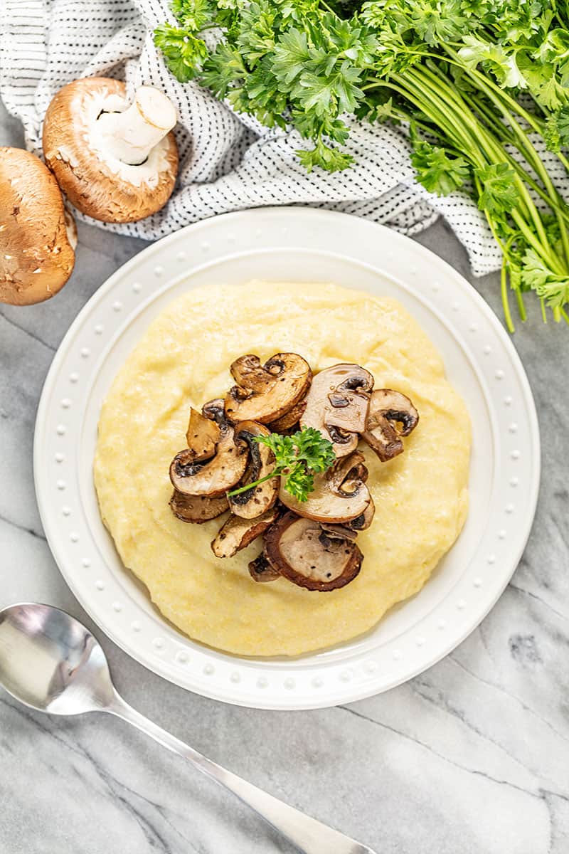 Bird's eye view of Polenta topped with mushrooms on a white plate.