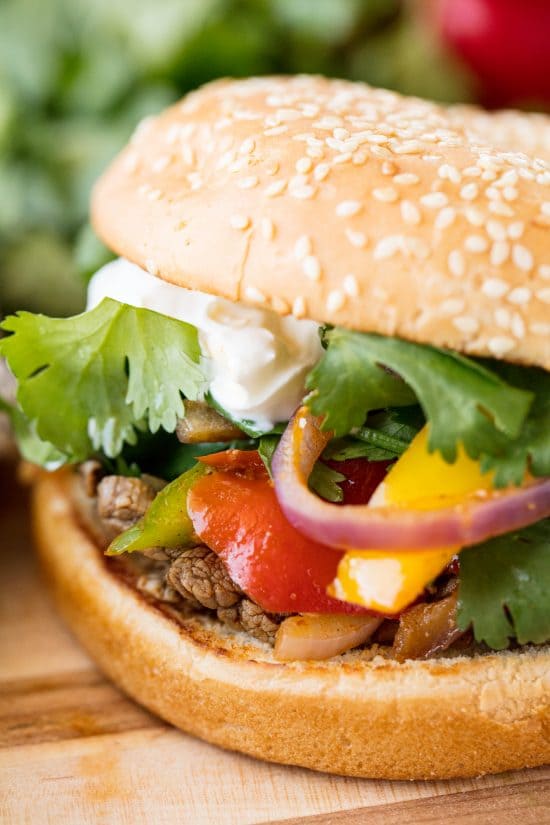 Fajita Burgers with grilled steak, bell pepper, red onion, cilantro and sour cream on a Sesame Bun