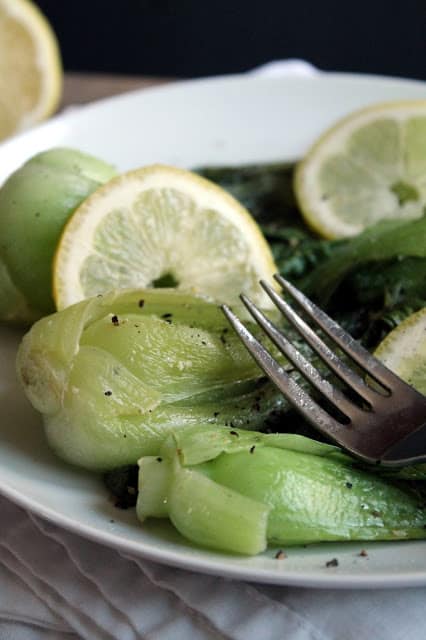 Lemon-Garlic Baby Bok Choy on a white plate with a fork on it. 