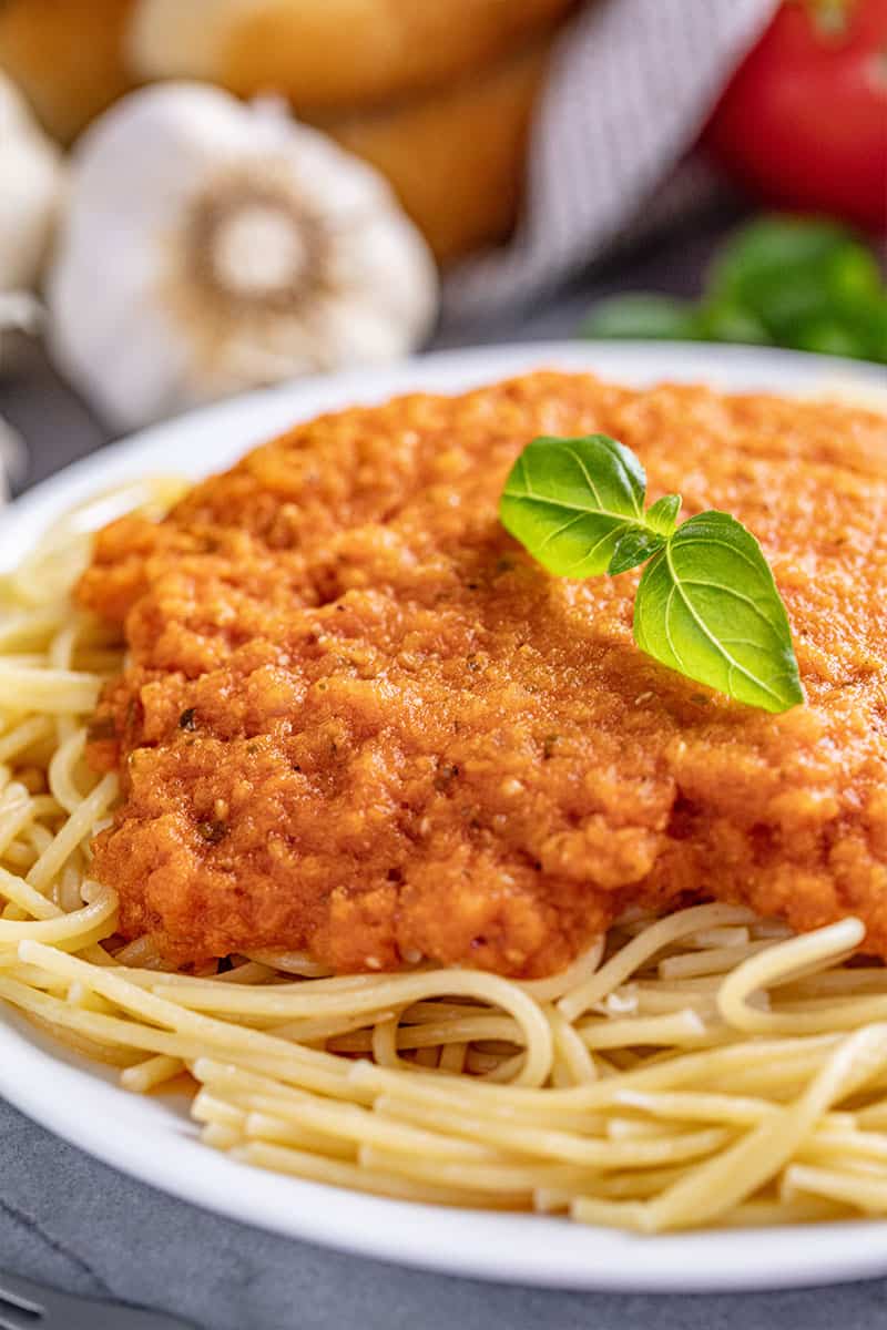 Fire Roasted Spaghetti Sauce over spaghetti and garnished with a sprig of fresh basil