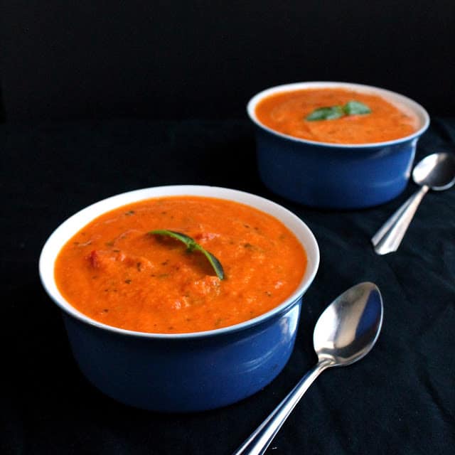 Two bowls of tomato soup sitting next to each other.