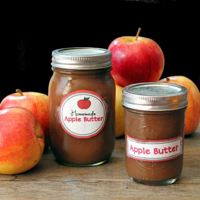 Two mason jars full of apple butter sitting next to some apples.