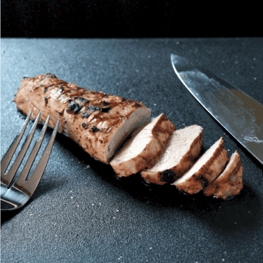 Pork Tenderloin with half of it sliced up an on a black countertop.