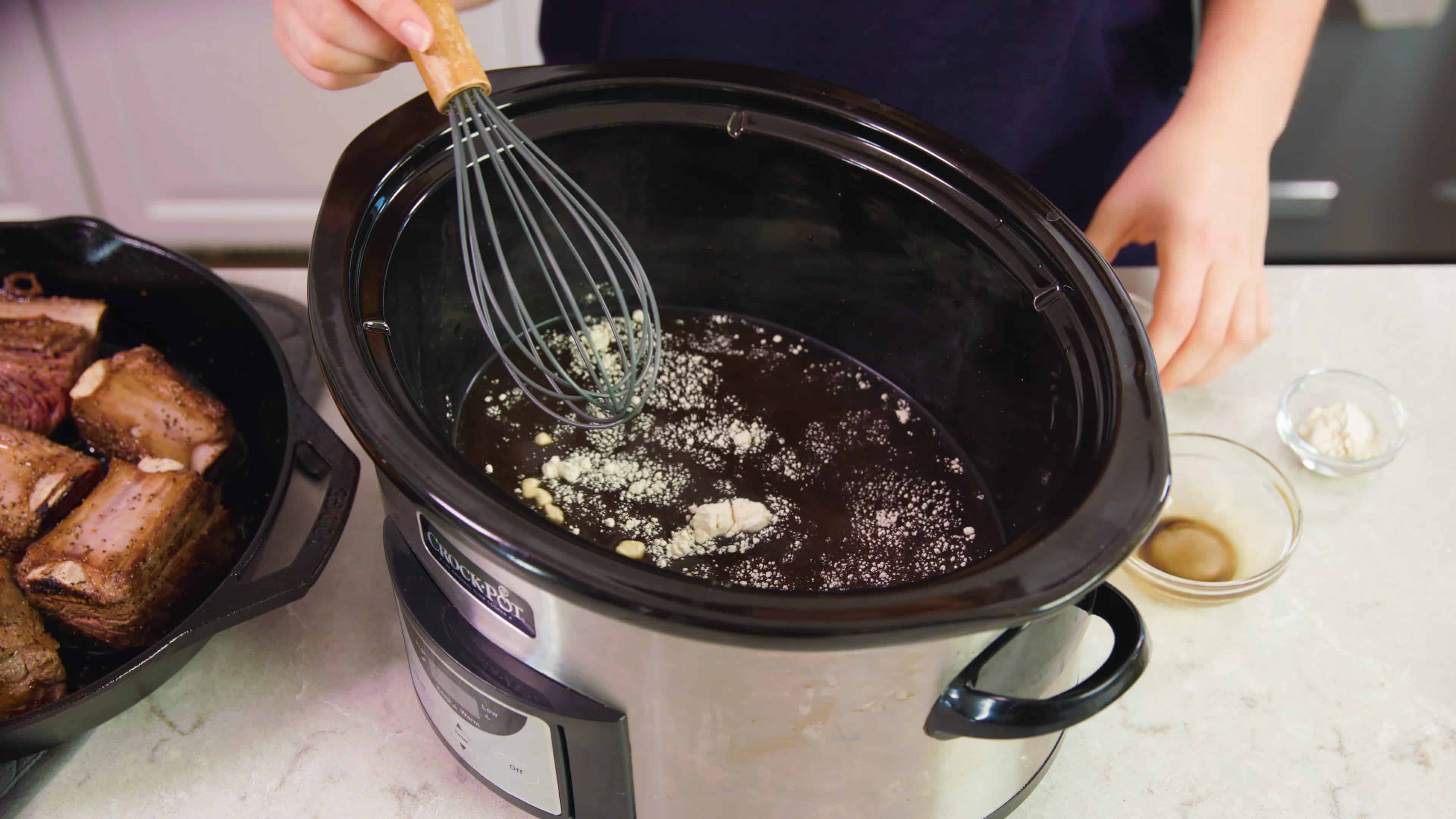 Whisking ingredients placed in a slow cooker.