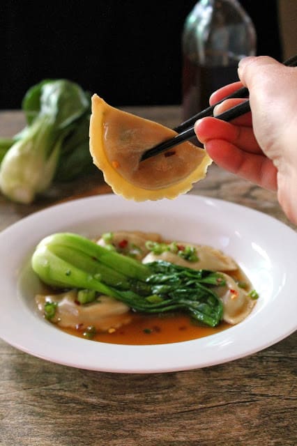 A dumpling getting pulled out of a bowl of soup.