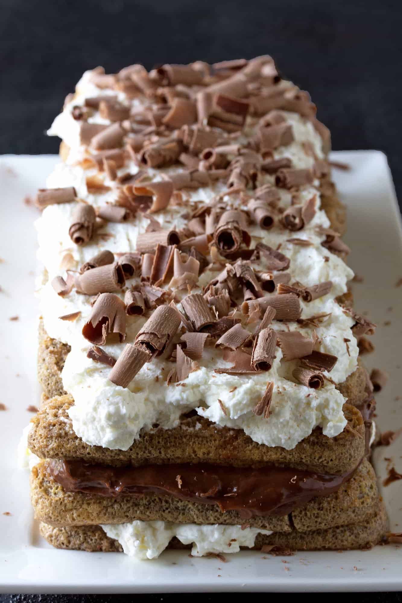 Layered tiramisu served on a platter and topped with chocolate curls.