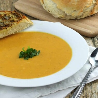 Healthy Harvest Soup in a white bowl with a slice of bread on it.