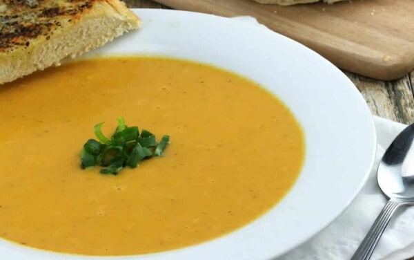 Healthy Harvest Soup in a white bowl with a slice of bread on it.