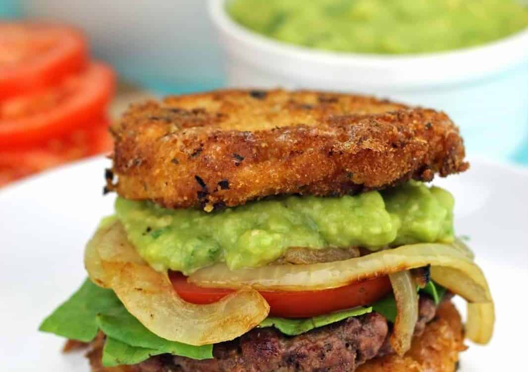 Mac and Cheese Burgers with Guacamole and Grilled Onions sitting on a white plate.