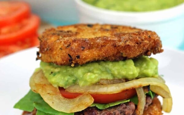 Mac and Cheese Burgers with Guacamole and Grilled Onions sitting on a white plate.