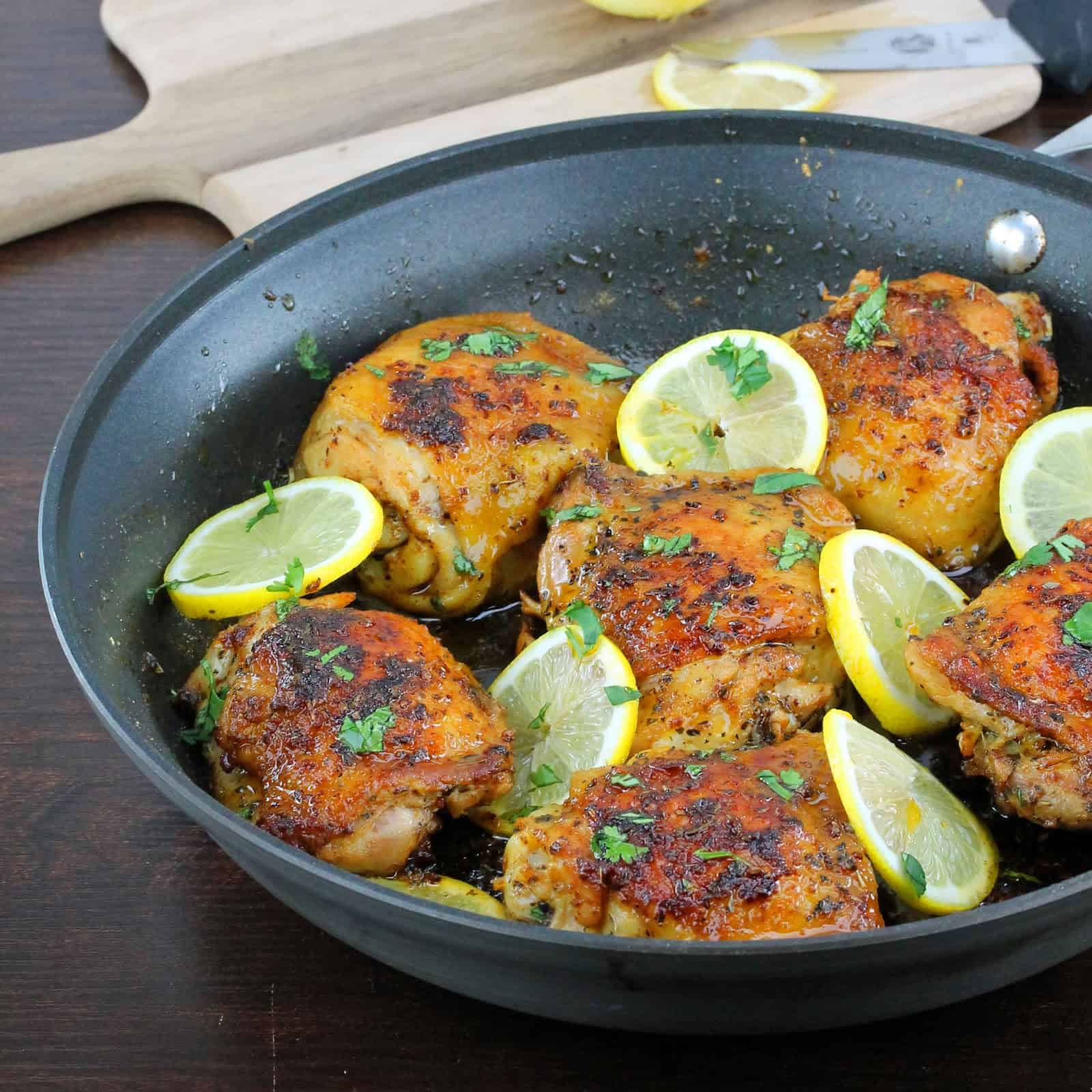 Skillet Chicken Thighs in a skillet topped with lemon slices.
