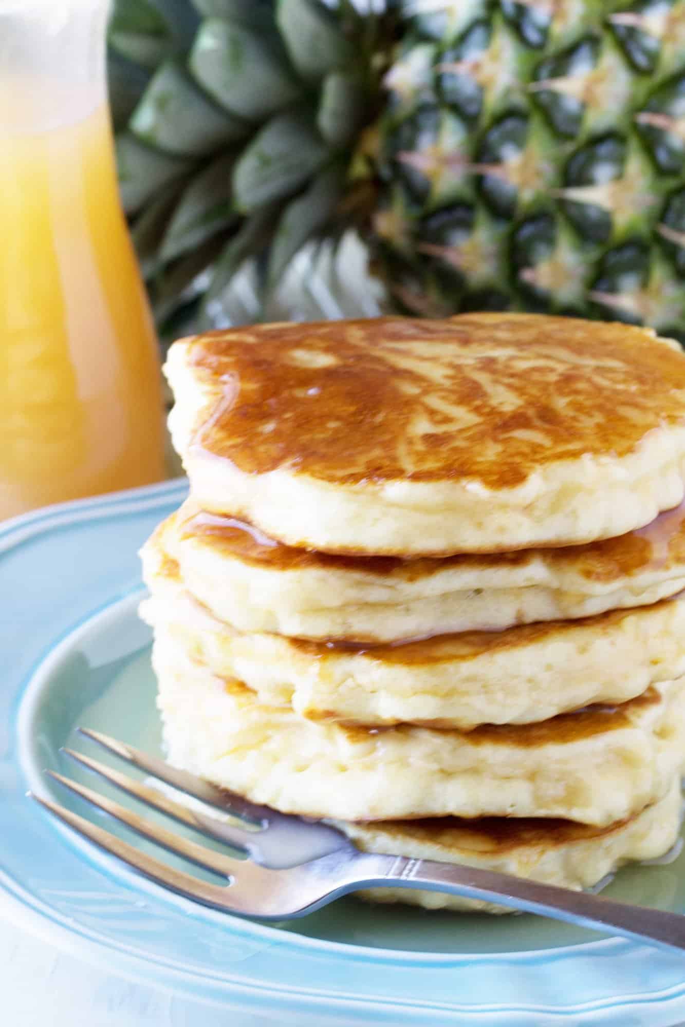 Pineapple Pancakes with Coconut Syrup over them on a blue plate.