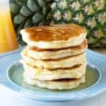 Pineapple Pancakes with Coconut Syrup over them on a blue plate.