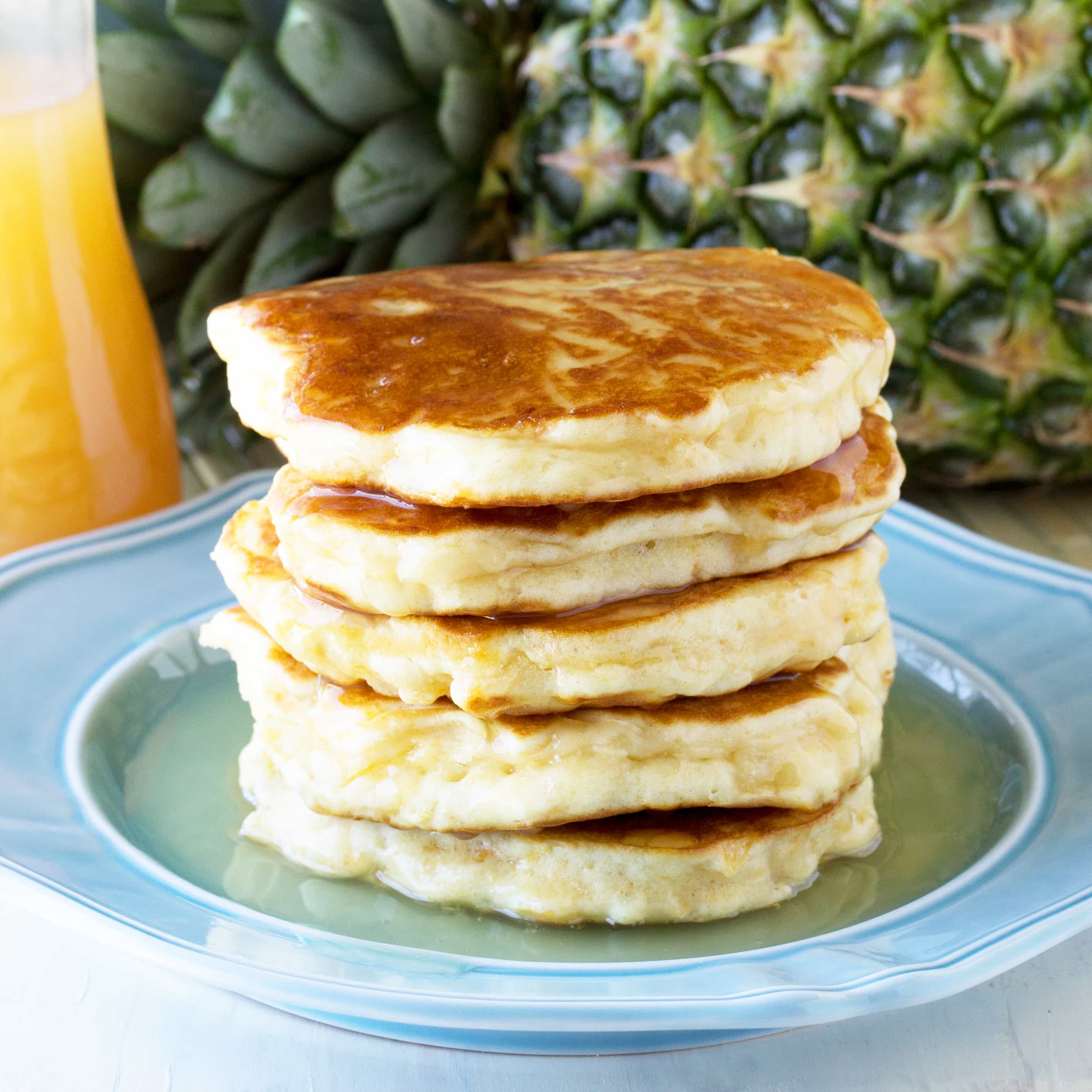 Pineapple Pancakes with Coconut Syrup over them on a blue plate.