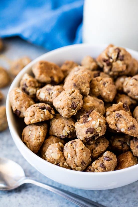 Bowl of homemade cookie cereal with a spoon and glass of milk on the side