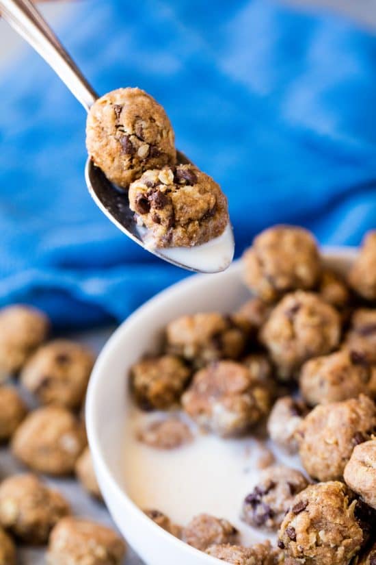 A spoonful of homemade cookie cereal and milk, with a full bull of cereal and milk in the background