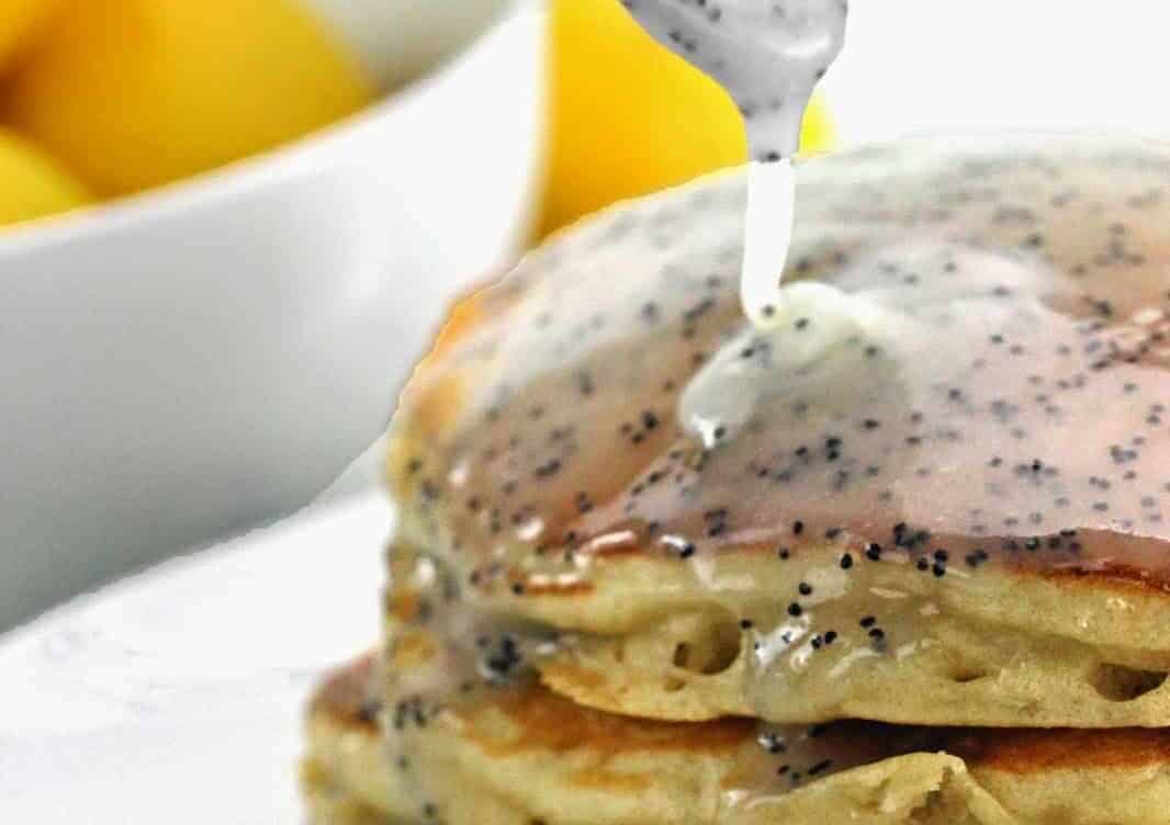 Lemon Poppyseed Buttermilk Syrup being poured on a stack of pancakes.