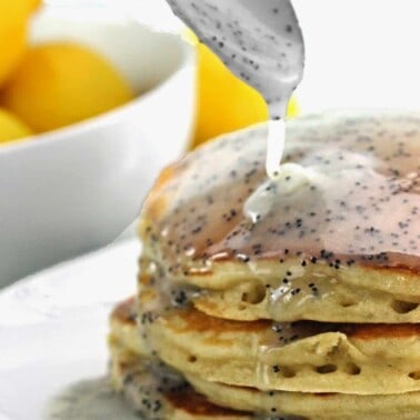 Lemon Poppyseed Buttermilk Syrup being poured on a stack of pancakes.