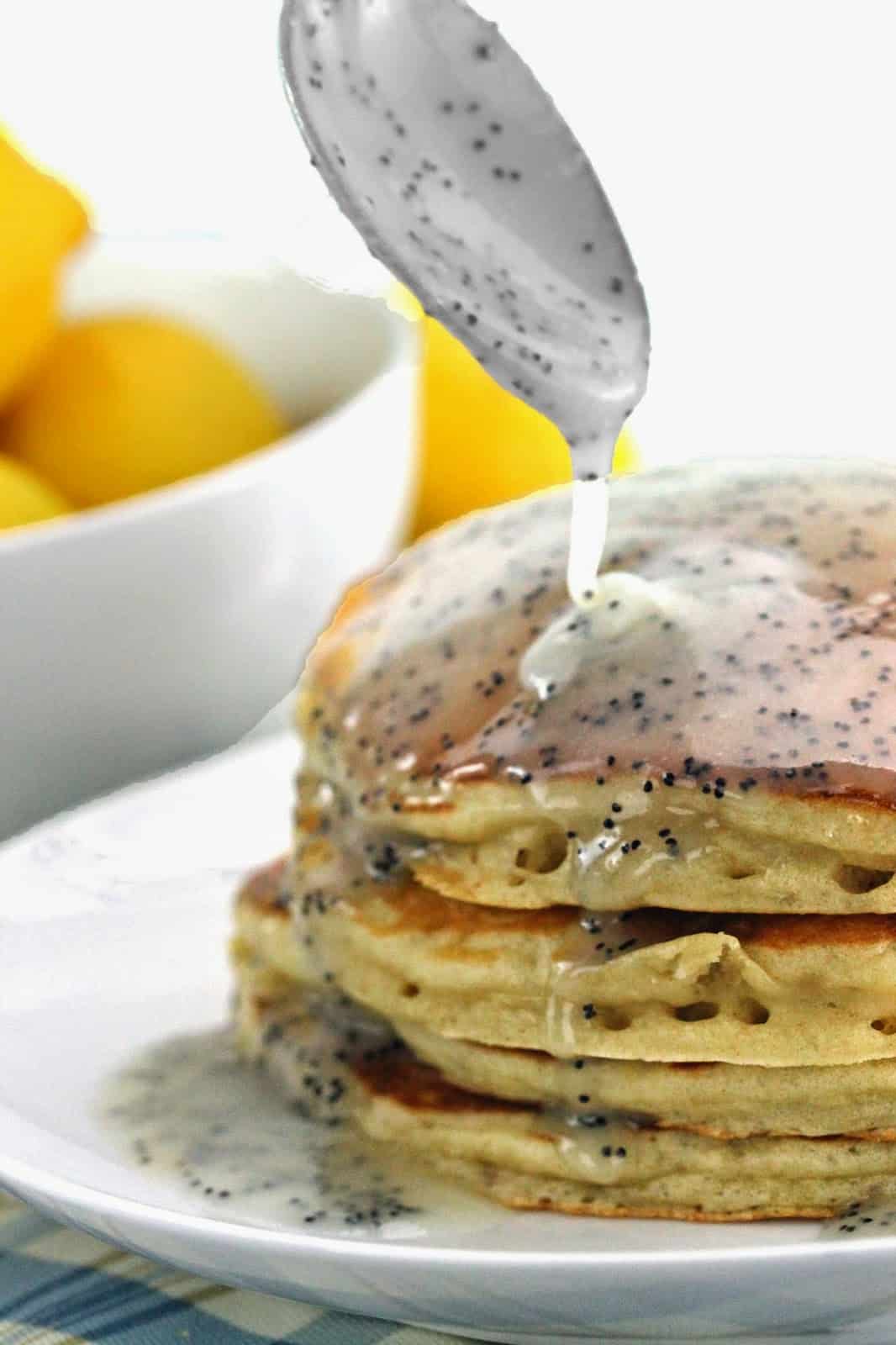 Lemon Poppyseed Buttermilk Syrup being poured on a stack of pancakes.