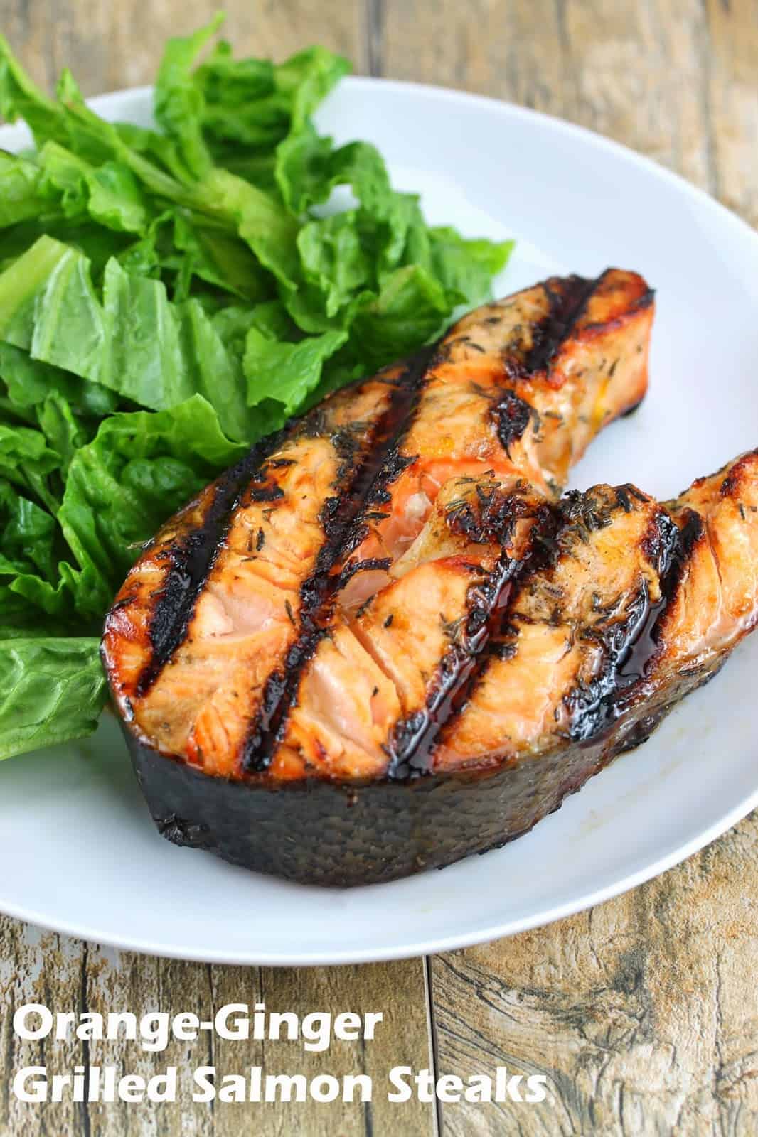 Orange ginger grilled salmon steaks on a white plate with a salad