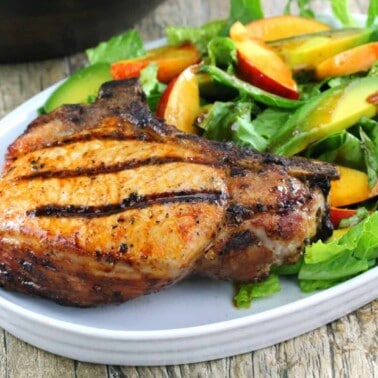 Grilled Pork Chop and a Nectarine and Avocado Salad on a white plate.