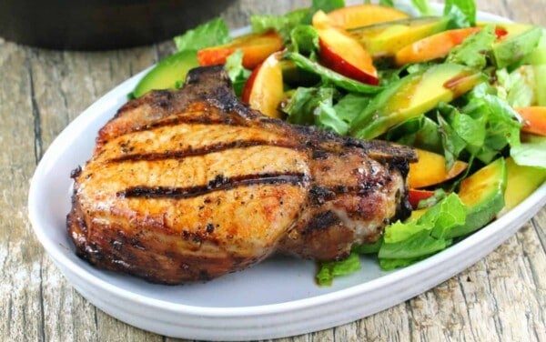 Grilled Pork Chop and a Nectarine and Avocado Salad on a white plate.