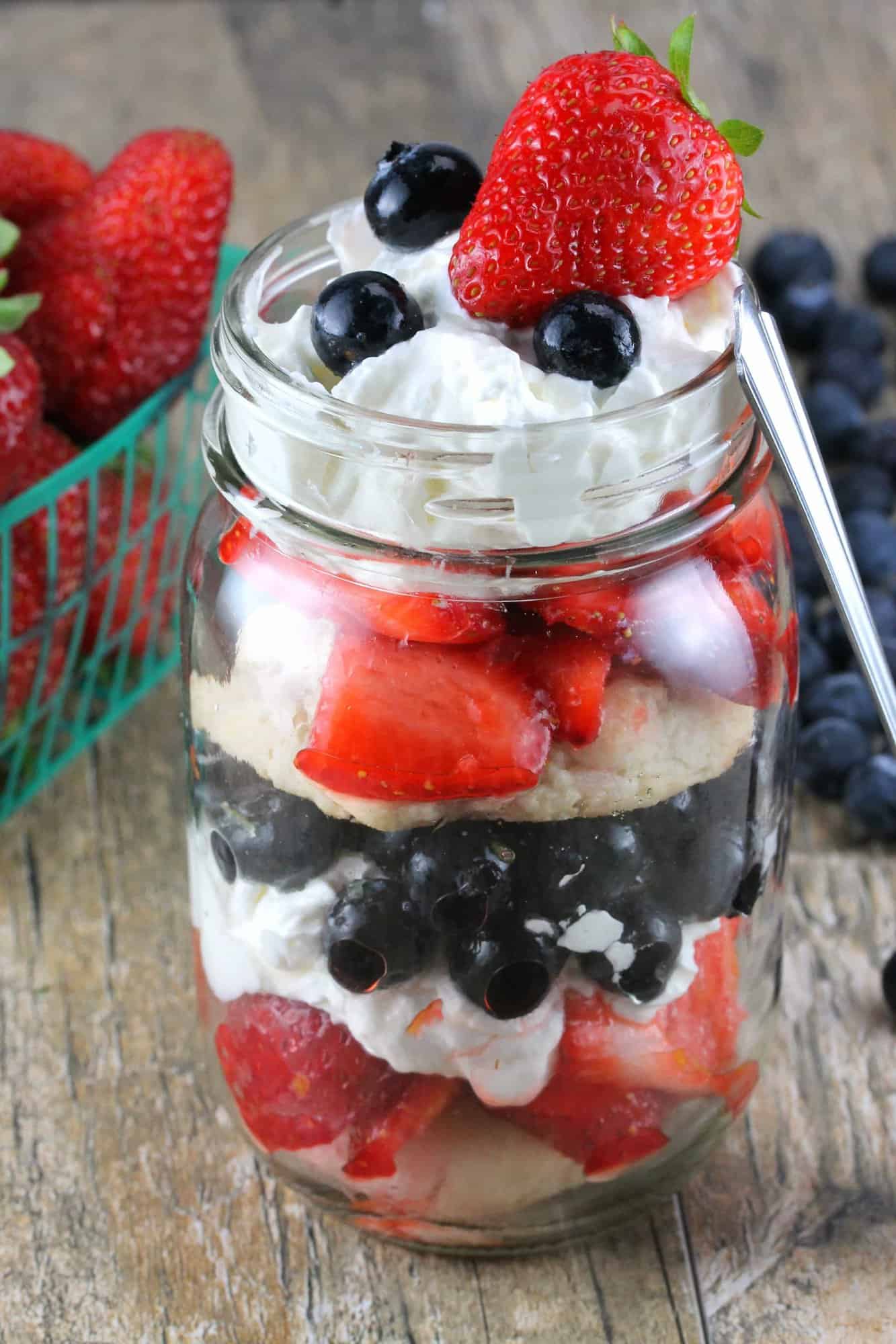 Close up of Red, White, and Blueberry Mason Jar Shortcake on a wooden counter.