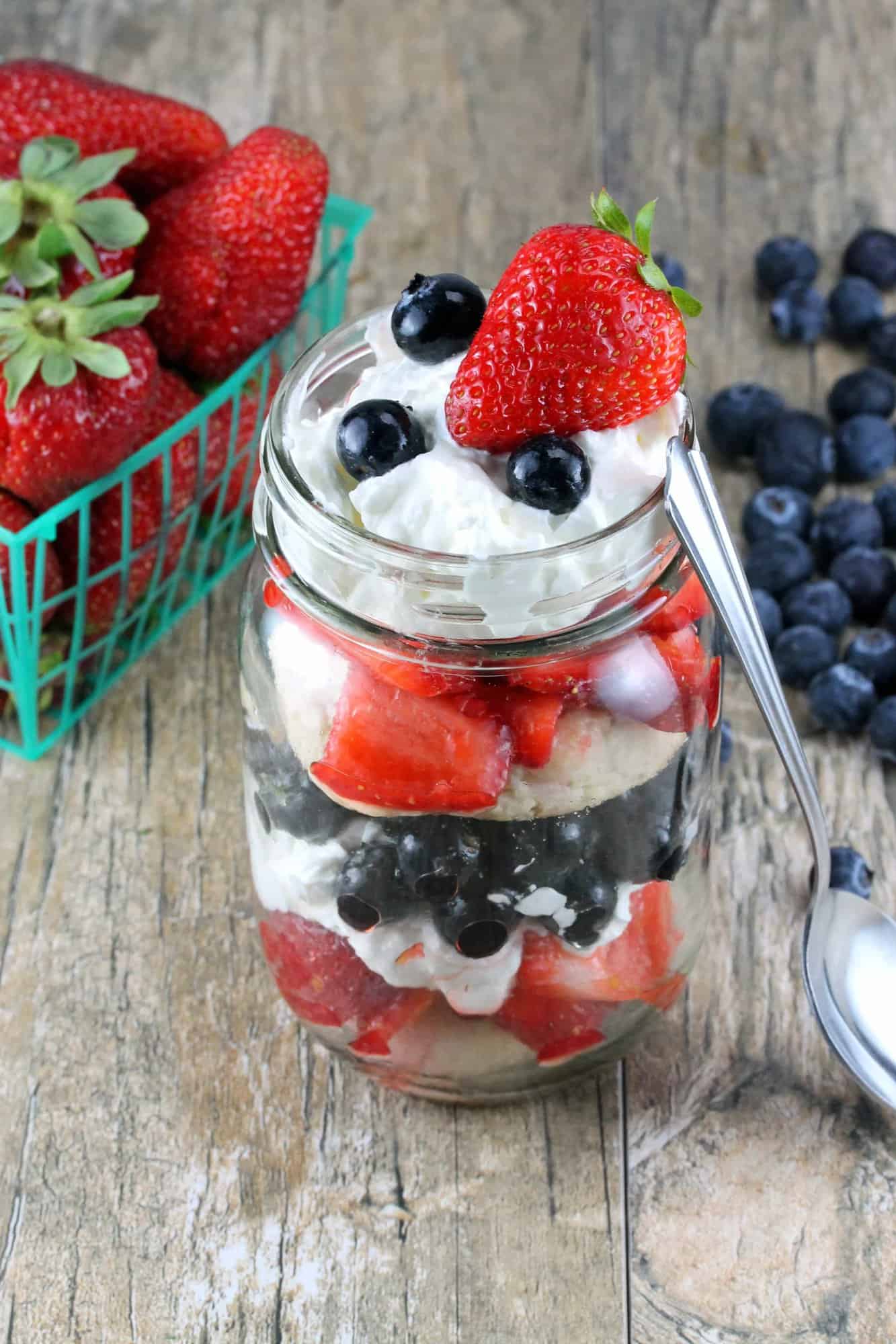 Red, White, and Blueberry Mason Jar Shortcake on a wooden counter.