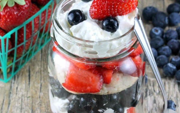 Red, White, and Blueberry Mason Jar Shortcake on a wooden counter.